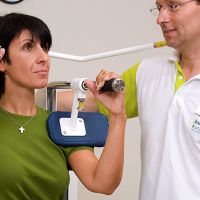 Eine Patientin mit einem Physiotherapeut am Trainingsgerät